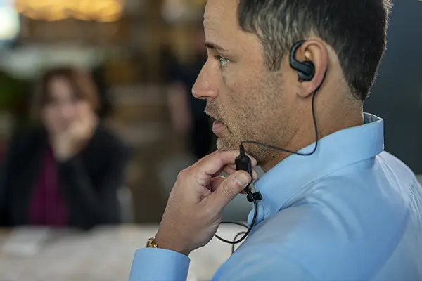 Person using wired earpiece with integrated microphone in an indoor setting