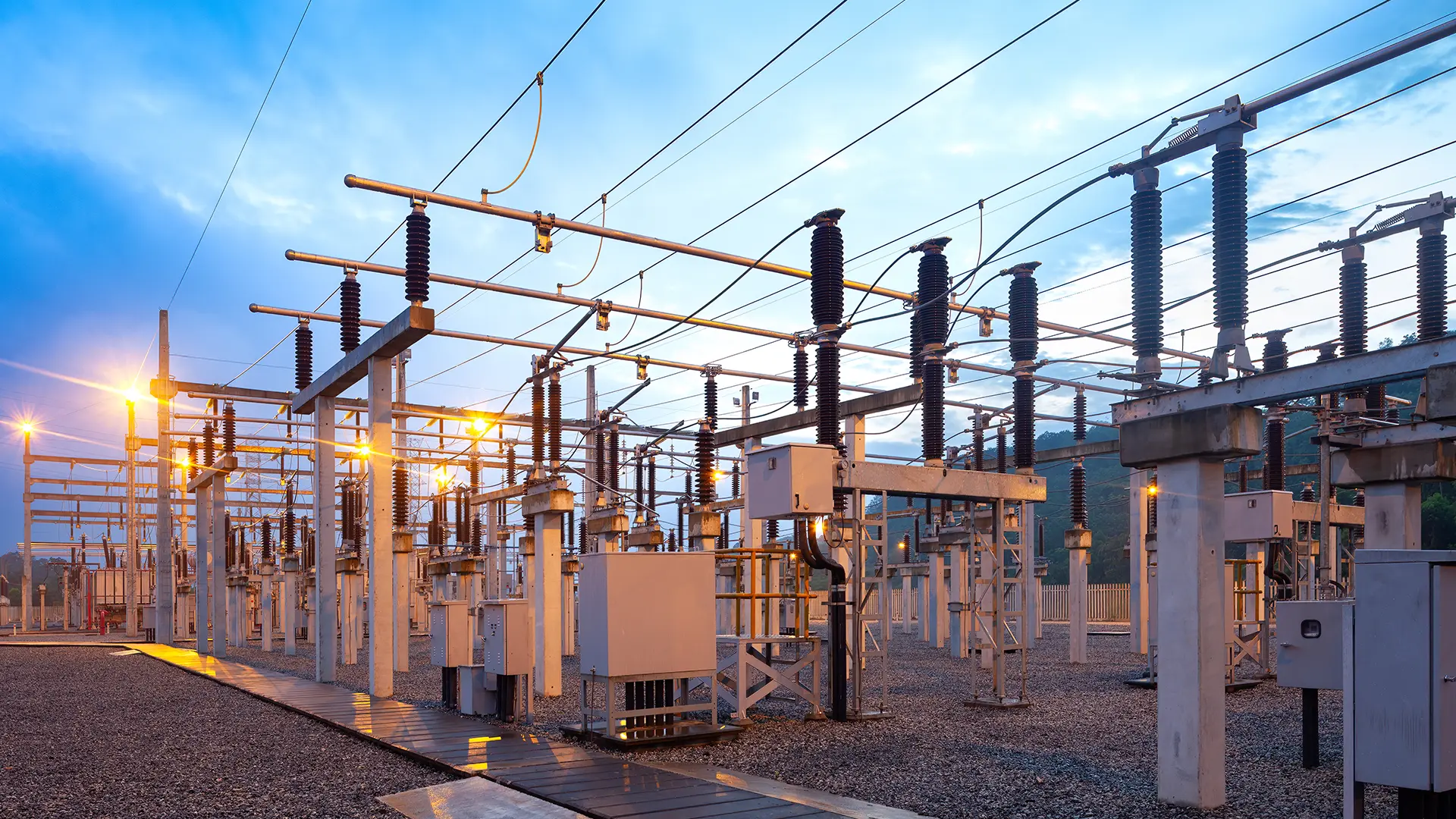 Electrical substation with high-voltage equipment illuminated at dusk