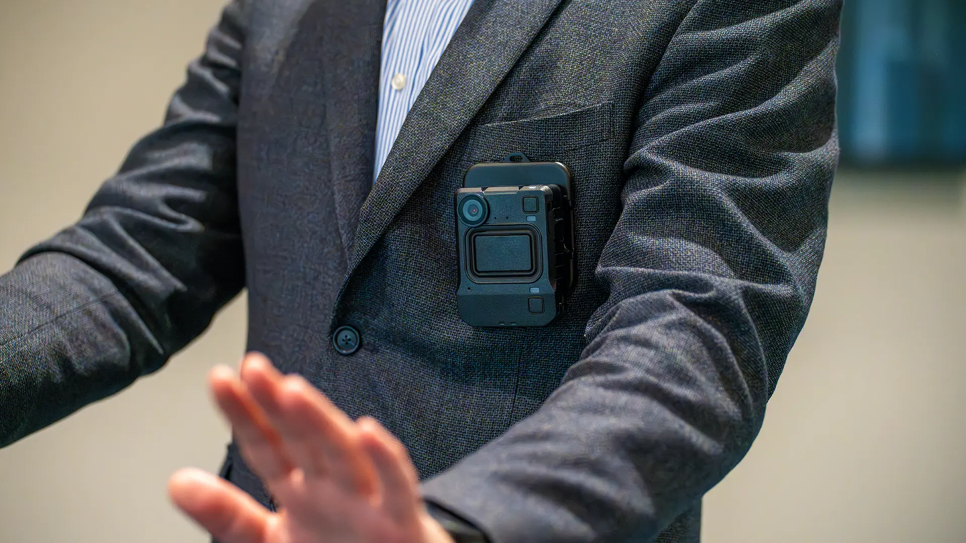 Person in a suit with a Motorola Solutions body worn camera attached to the lapel, raising hands to de-escalate a situation.