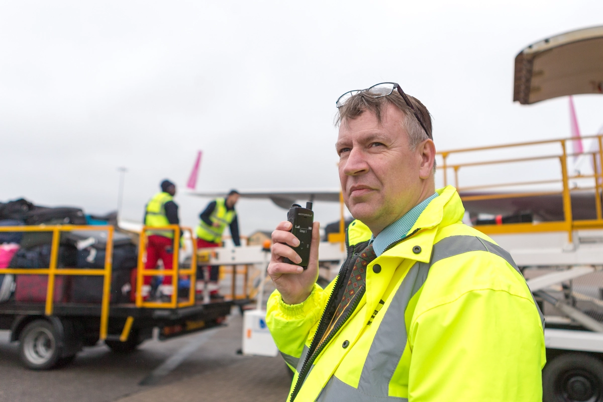 Airport ground worker using Motorola Solutions radio to communicate with team
