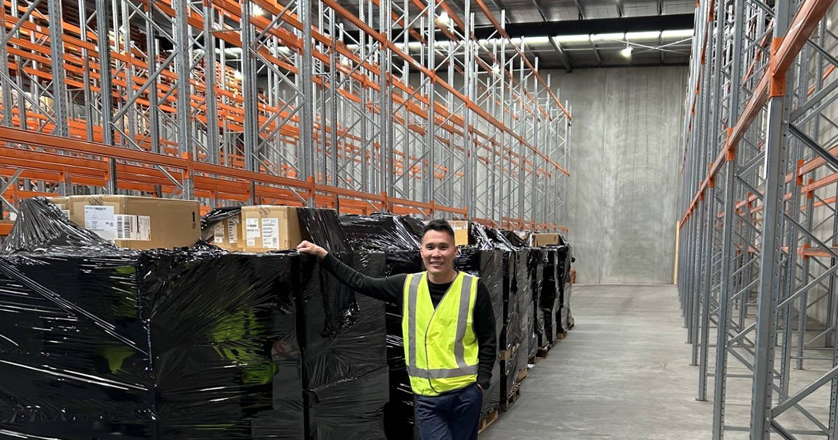 Logic Technologies team member poses with a delivery of stock to an empty warehouse.